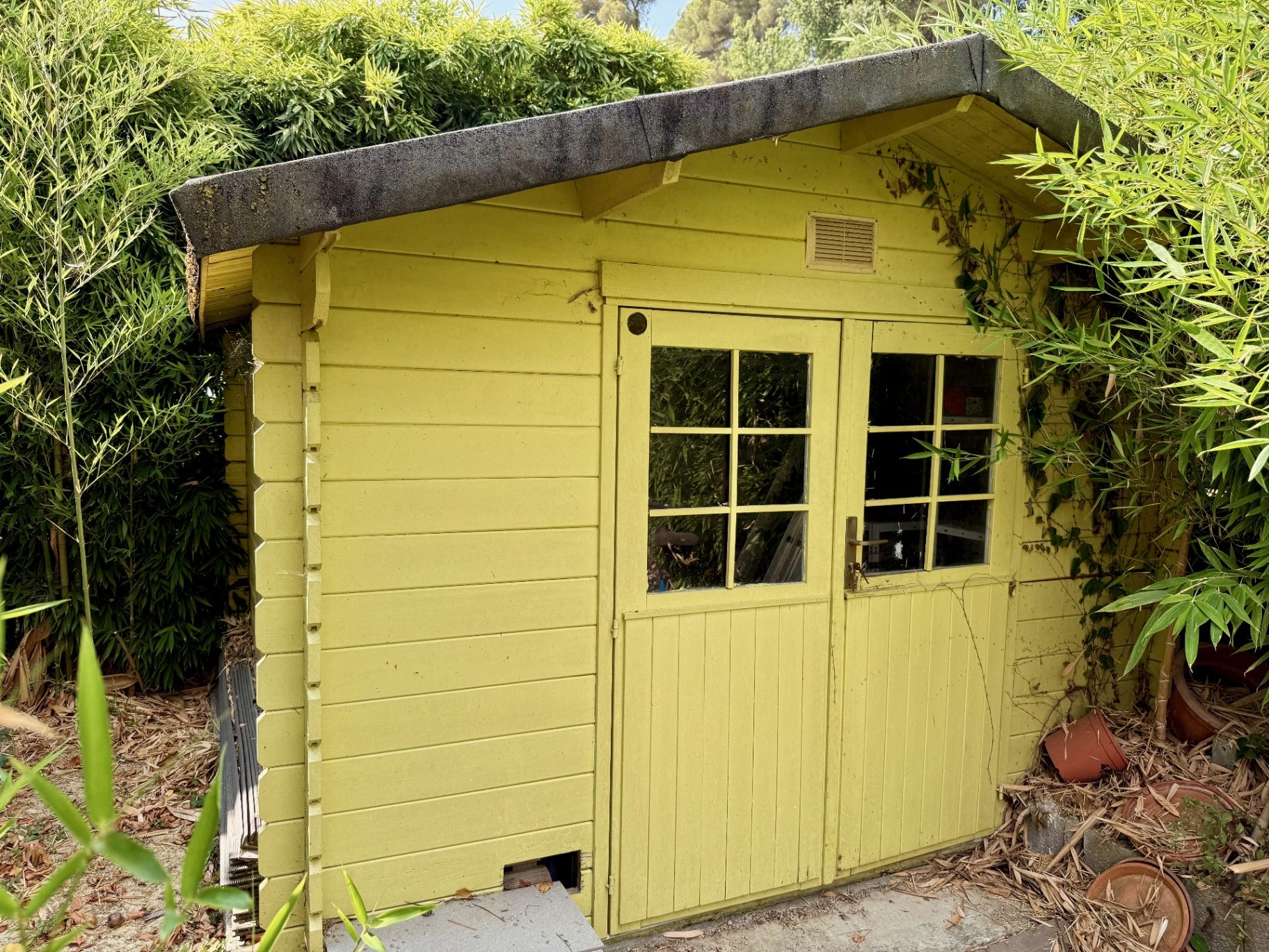 Cabanon jaune aménagé niché dans les bambous